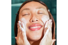 Image A woman washing her face while smiling.